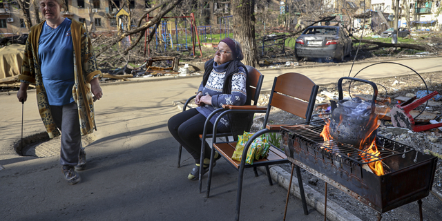 Las mujeres locales se reúnen en la entrada de un edificio de apartamentos destruido en Mariupol, Ucrania, el martes 26 de abril.
