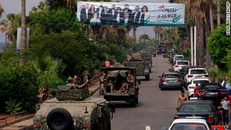 Los vehículos del ejército libanés pasan frente a una valla publicitaria que representa a los candidatos para las elecciones parlamentarias el domingo en Beirut, Líbano, el 14 de mayo.