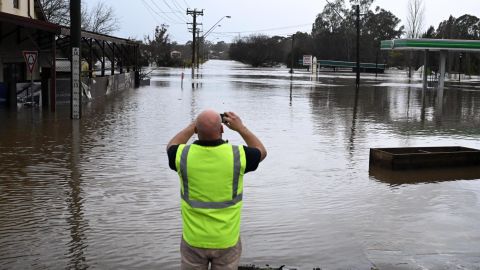 Un ciudadano local toma una foto de una carretera inundada en Camden, en el suroeste de Sydney, el domingo 3 de julio de 2022.