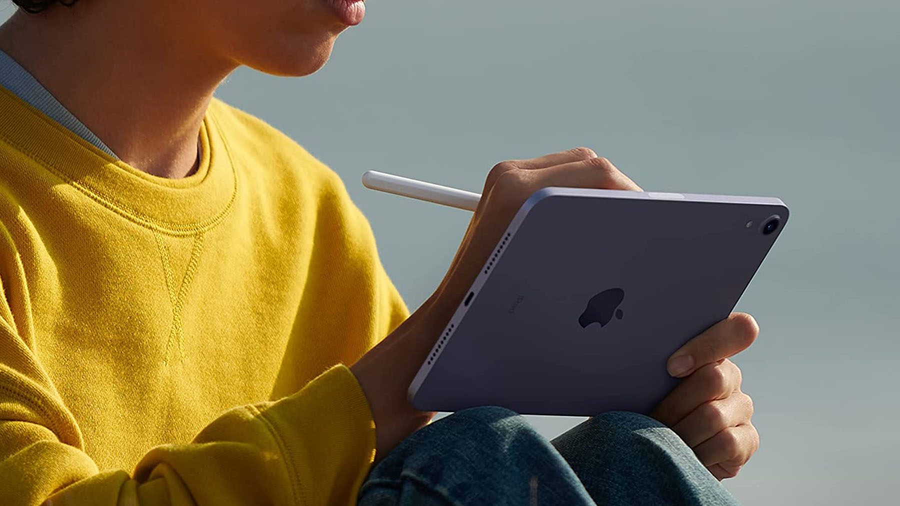 Una foto de una persona sentada en un iPad Mini mientras usa un Apple Pencil