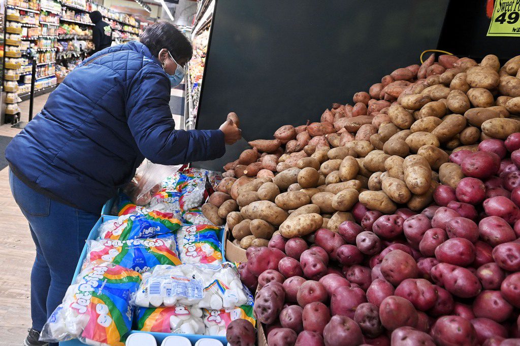 Una mujer reparte patatas en una tienda de comestibles.